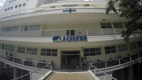 Fachada do ACISPES em São João Nepomuceno, destaque para a estrutura e movimento na entrada.