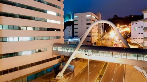 Vista noturna da ponte que conecta edifícios em São João Nepomuceno.